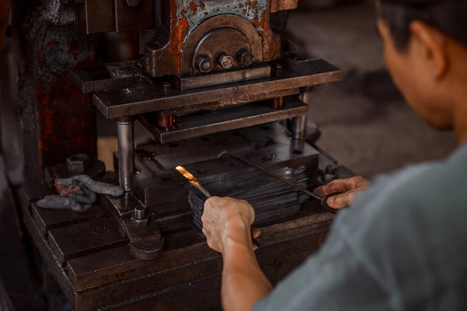 Close-up of worker using industrial press in metalworking process.